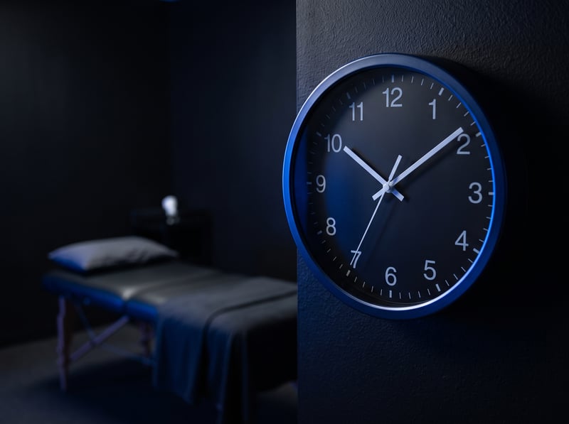 Analog clock in front of an empty treatment table